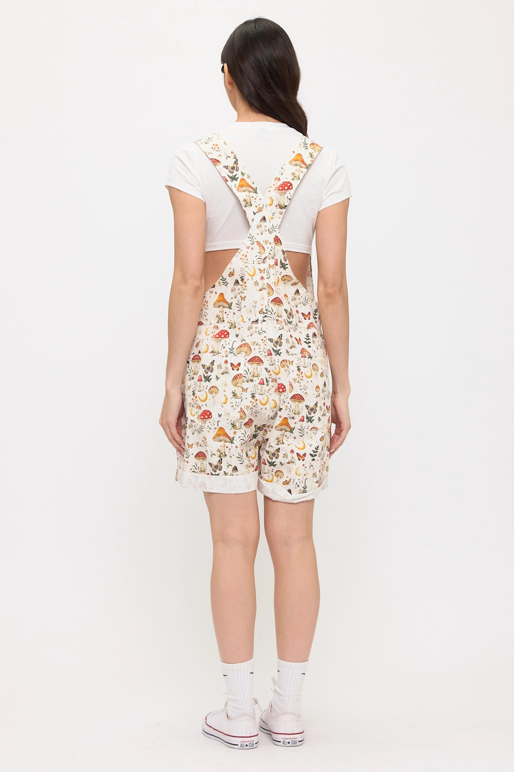 Boho woodland mushroom print overall romper with butterflies and moon motifs layered over a white short sleeve tee, styled as a whimsical cottagecore outfit.